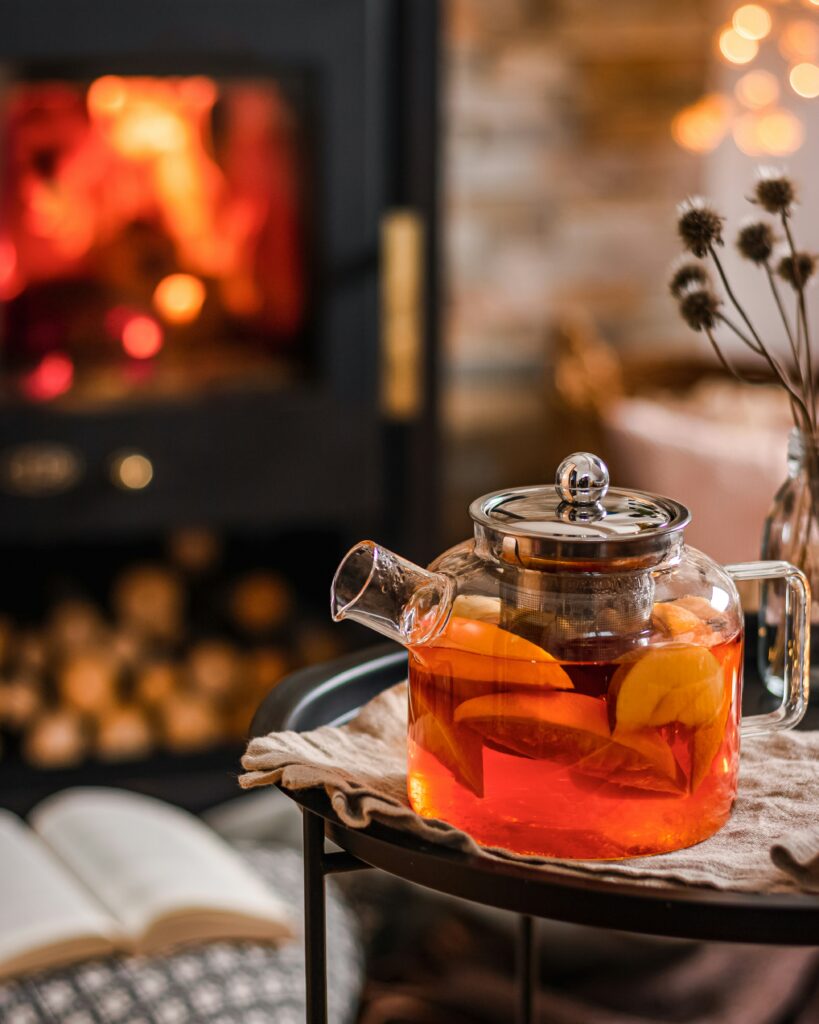 A beautiful tea kettle with lemon tea, a cozy evening near a blazing fireplace 
