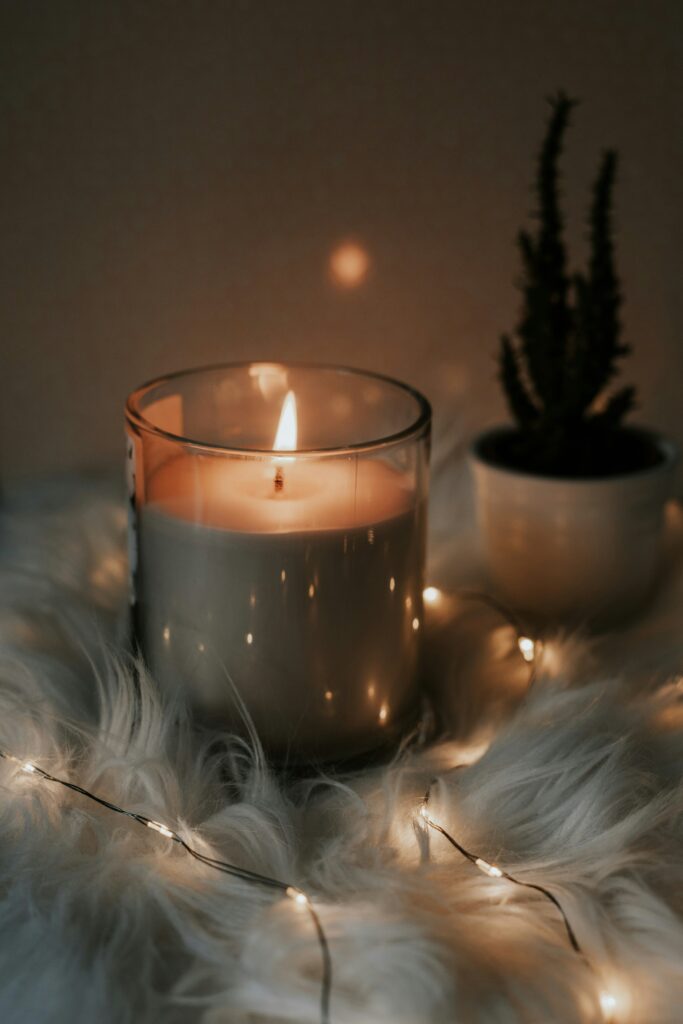 A candle, fur sheets, and string lights on a warm cozy evening.