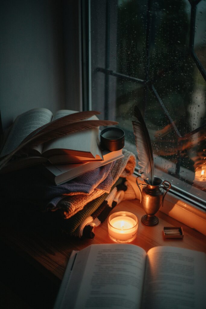 Beautiful open books, rainy night, light candles creating a cozy slow living aesthetic