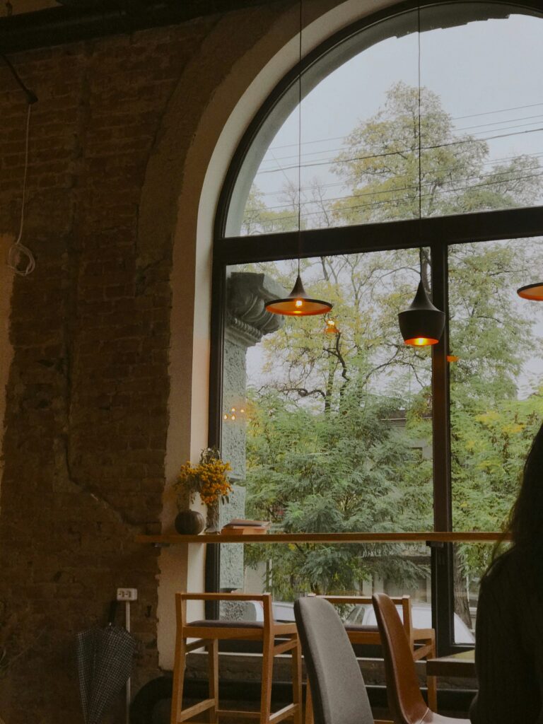 Arch-shaped café window with warm natural light creating a cozy and peaceful atmosphere inside a charming café