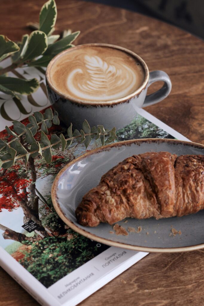 A warm latte and flaky croissant on a cozy café table, symbolizing the tiny everyday comforts that make life feel gentle again.