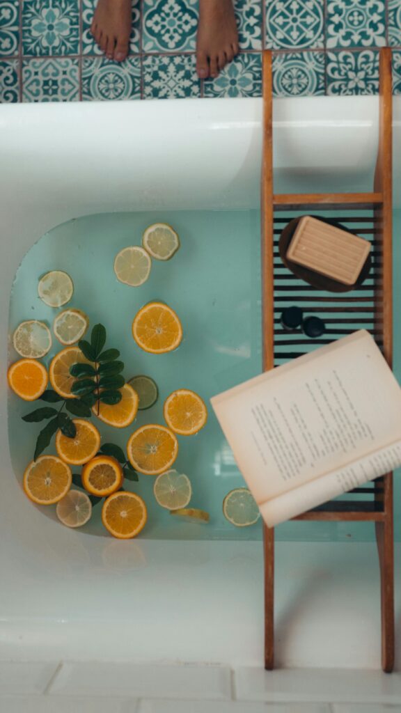 An aesthetic bath setup with citrus slices floating in water, an open book, and relaxing spa-like details.