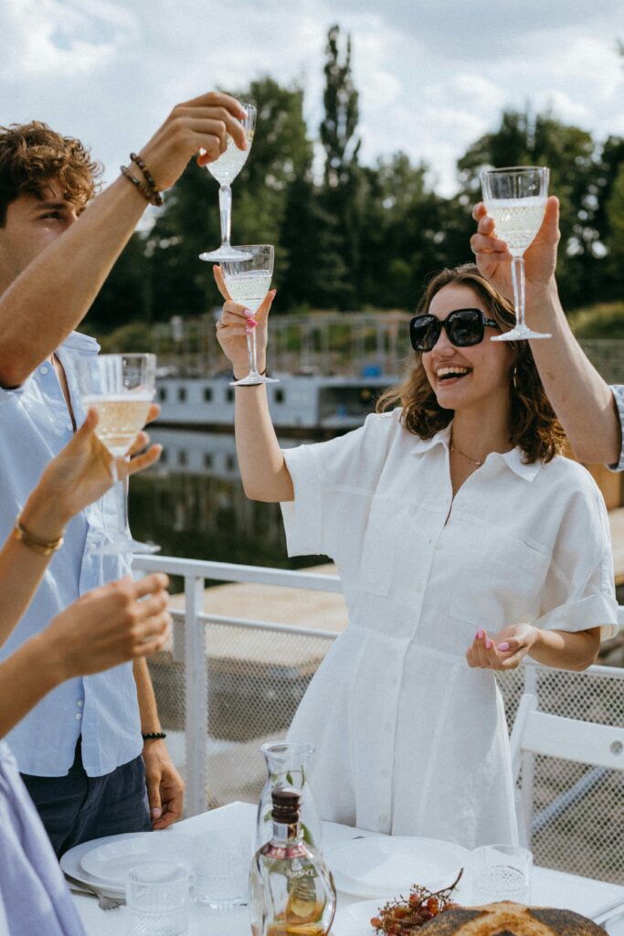 Group of friends enjoying a joyful toast with wine glasses on a sunny day, creating a non productive atmosphere.