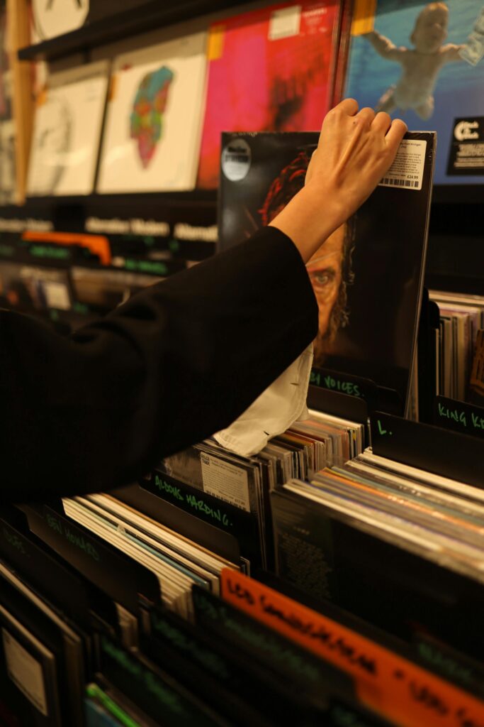 Person browsing through vinyl records in a warmly lit record store.