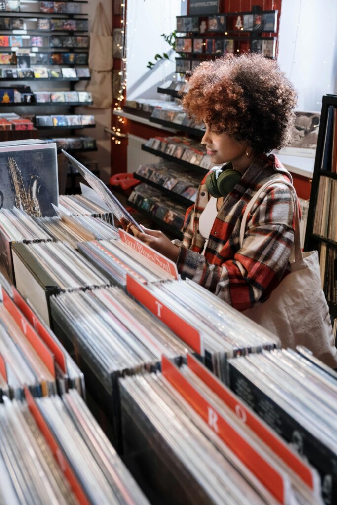 Person browsing through vinyl records in a warmly lit record store.