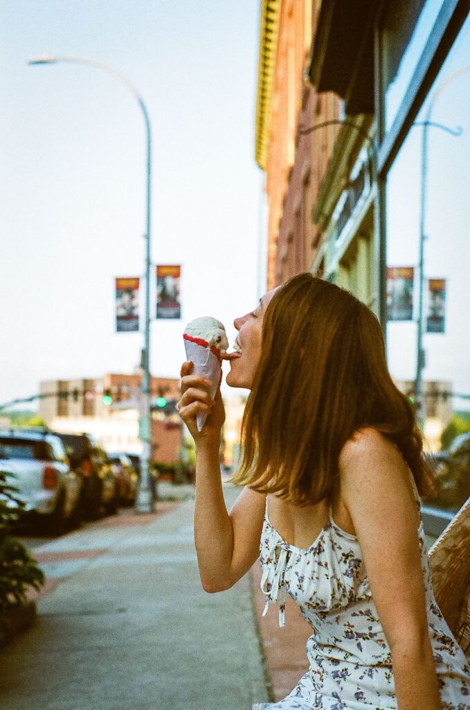 Happy woman eating ice cream on a sunny day, evoking nostalgic childhood summers before smartphones.