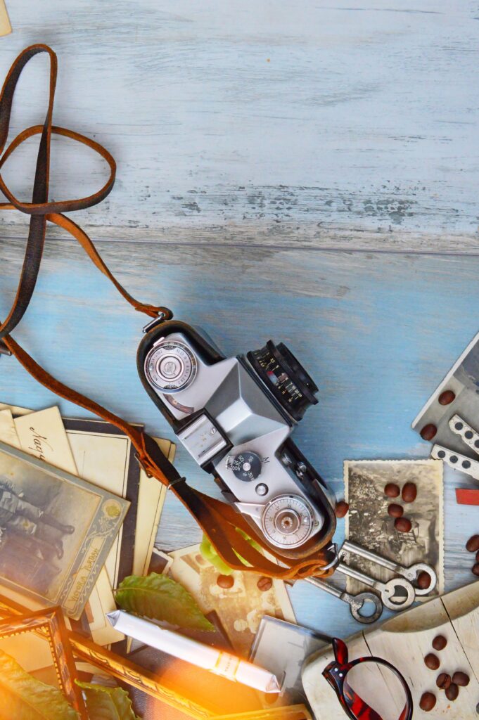 Vintage film camera surrounded by old printed photographs and coffee beans, creating a nostalgic analog living aesthetic.