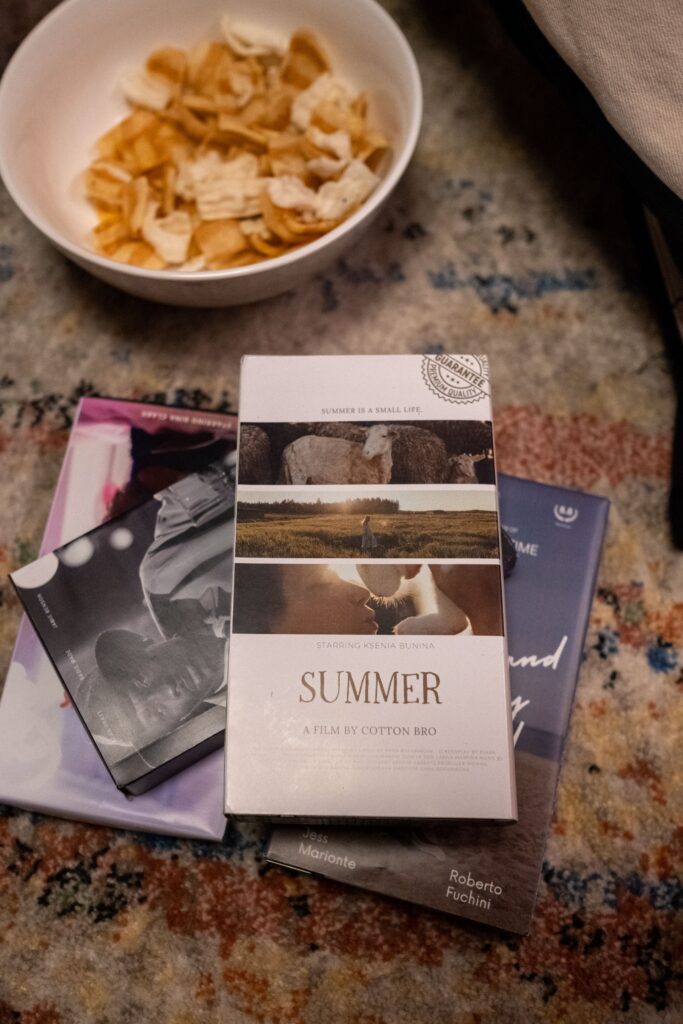 "Cozy movie night setup with snacks and films arranged on a rug, creating a nostalgic analog summer atmosphere."