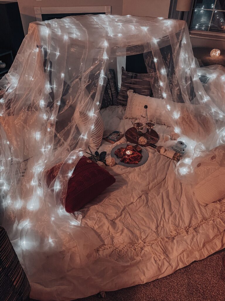 Cozy blanket fort decorated with fairy lights creating a magical childhood-inspired space.