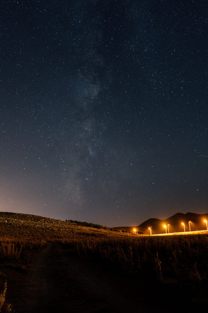"Star-filled summer night sky above a quiet countryside road, capturing the peaceful feeling of an analog summer evening."