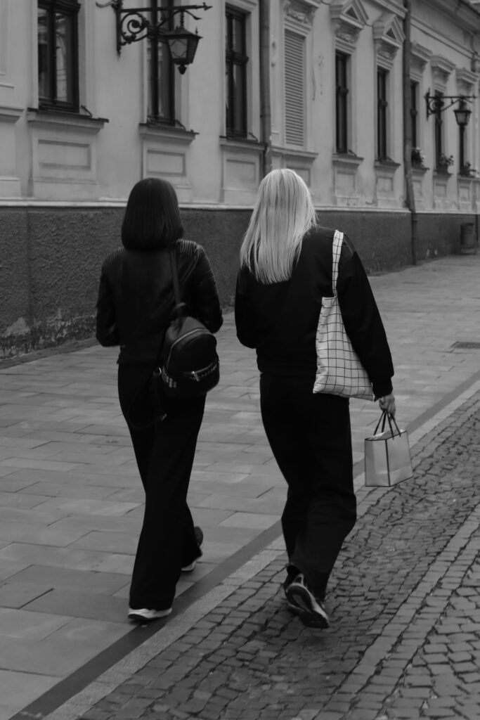 Two friends walking side by side along a quiet cobblestone street.