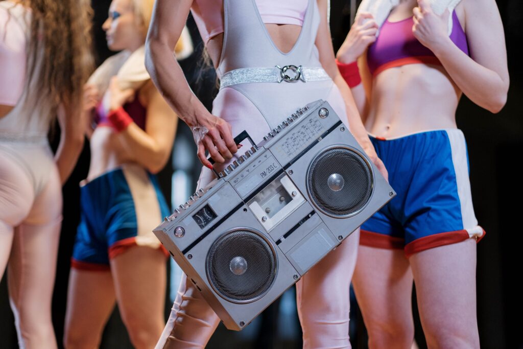 Vintage boombox held by a person in colorful retro workout clothing during an aerobics class.