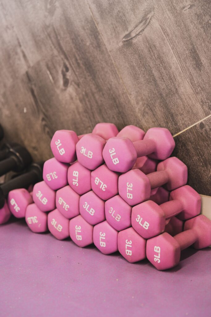 Stack of pink 3-pound dumbbells on a workout mat, representing fun and approachable fitness.