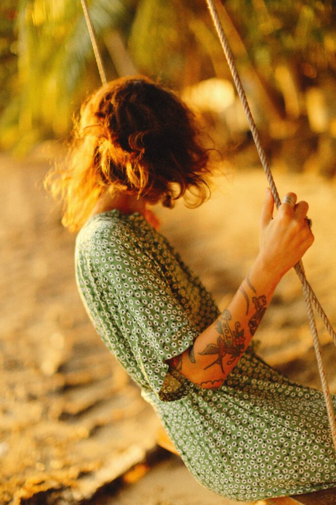 Person swinging on a rope swing during golden hour, surrounded by warm sunlight and nostalgic summer scenery.