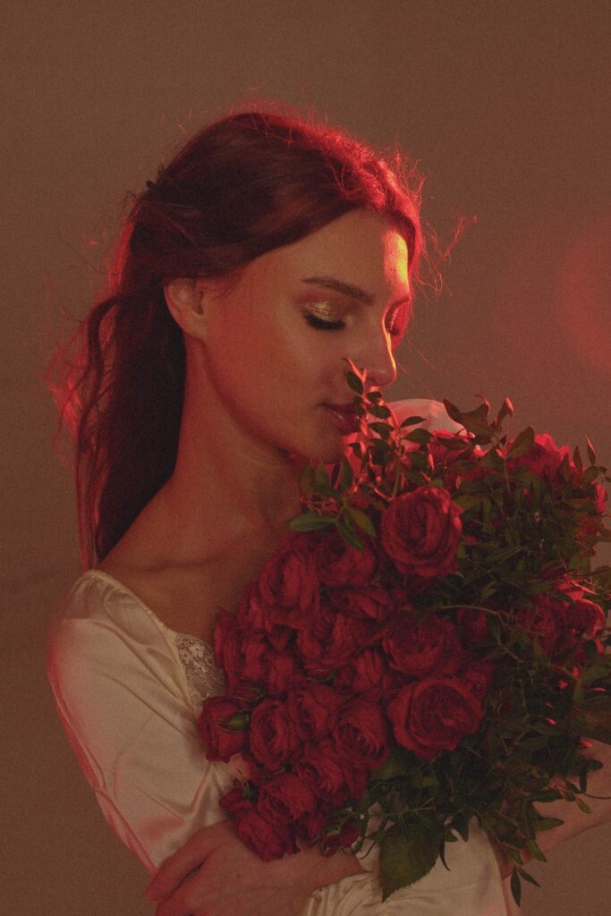 Woman holding a bouquet of red roses under soft romantic lighting, capturing a dreamy and cinematic mood.