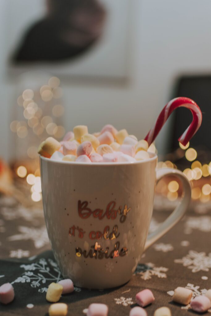 Cozy Christmas hot chocolate with colorful marshmallows candy cane and glowing Christmas lights creating a warm festive holiday atmosphere